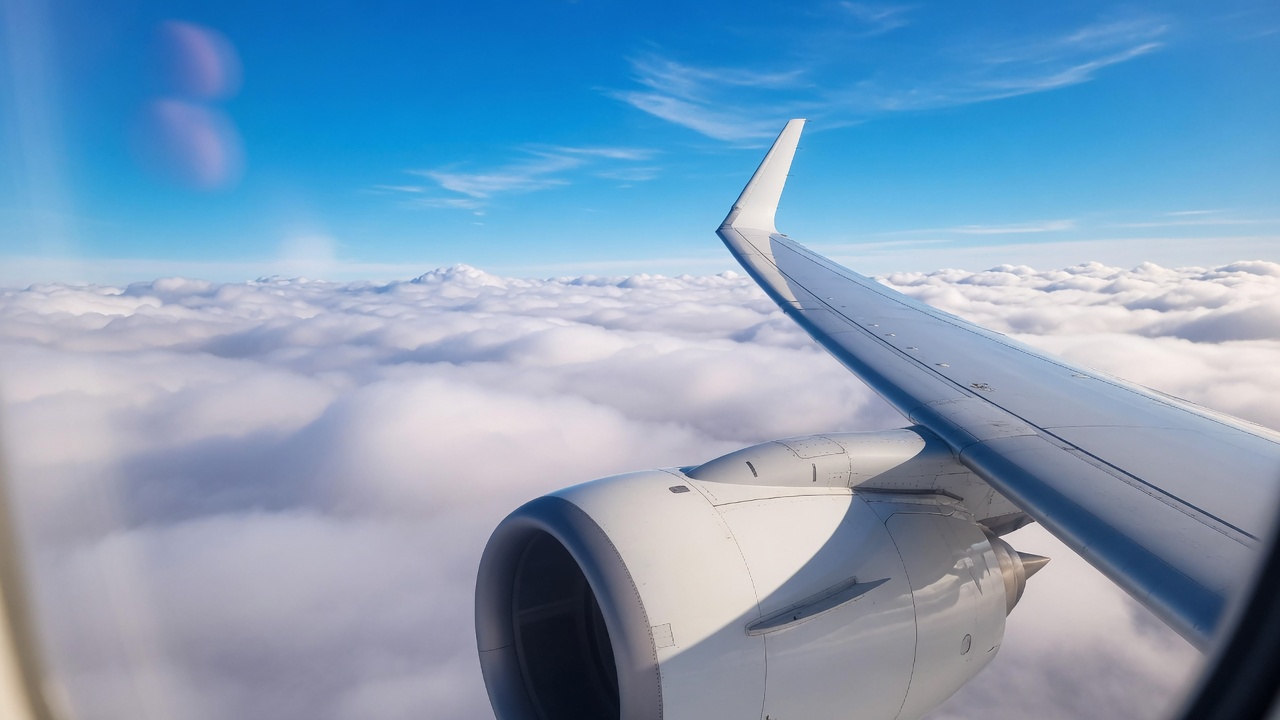 Airplane window view above clouds representing travel benefits